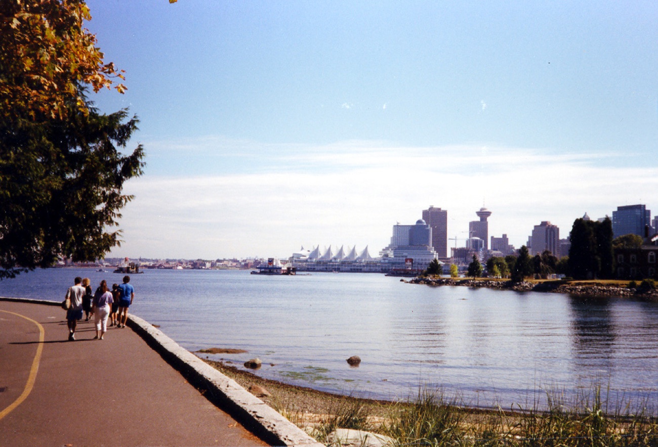 From the seawall in Stanley Park across Coal Harbour toward the Vancouver skyline, with the sail shaped roofs of Canada Place on the left